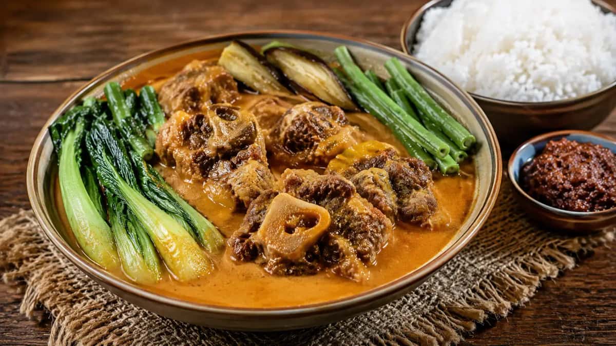 Filippinsk kare-kare med oxsvans och grönsaker i tjock jordnötssås serverad med bagoong