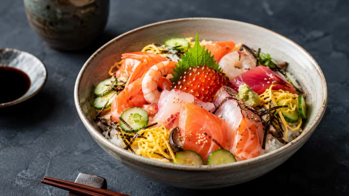 Autentisk japansk chirashi-sushi med lax, tonfisk, räkor och kinshi tamago över glansigt shari-ris